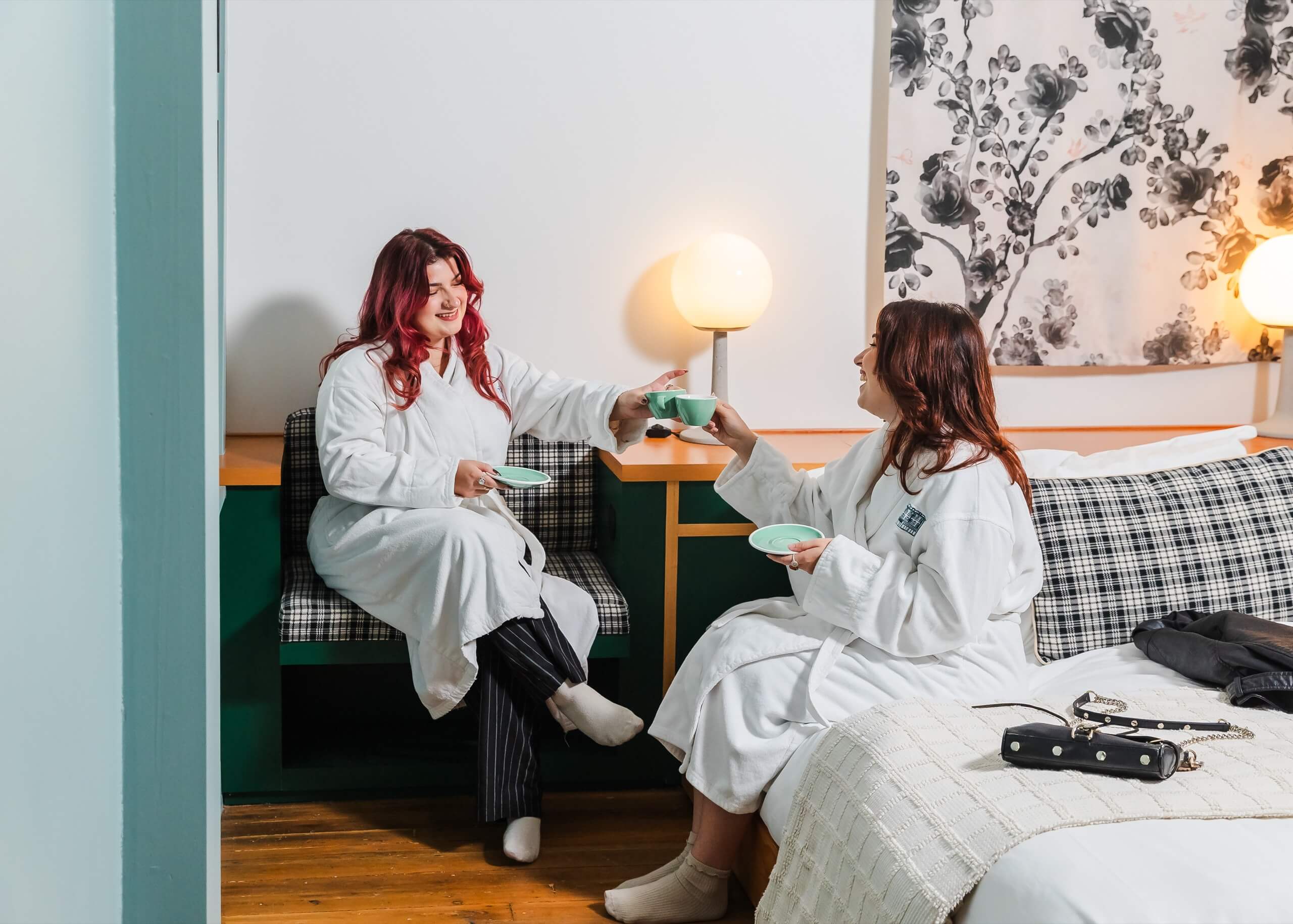 Two women in robes sitting in a hotel room