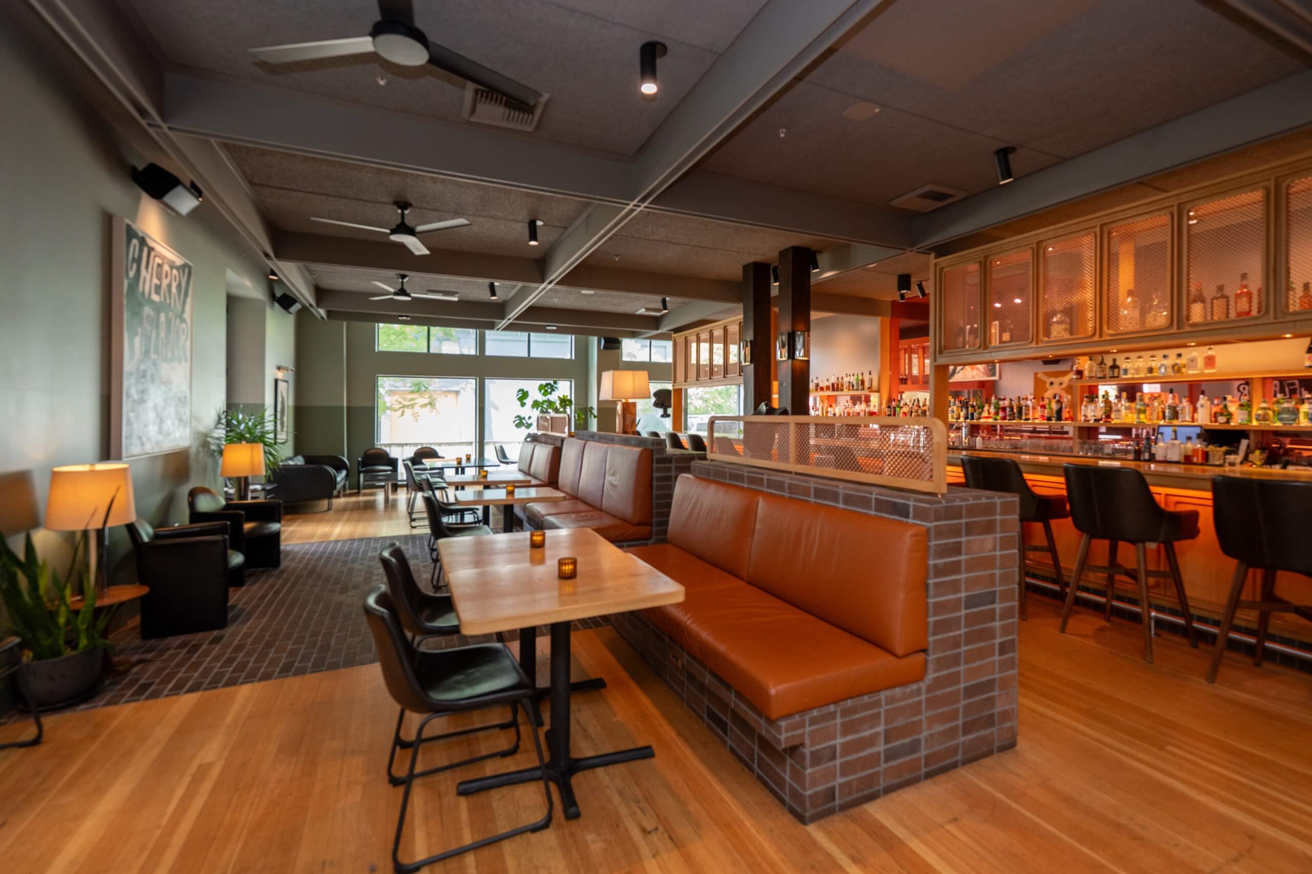 A hotel bar with a leather booth, wooden tables, and a bar counter.